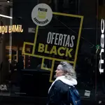 Una persona pasa por delante de una tienda que anuncia un cartel publicitario del Black Friday