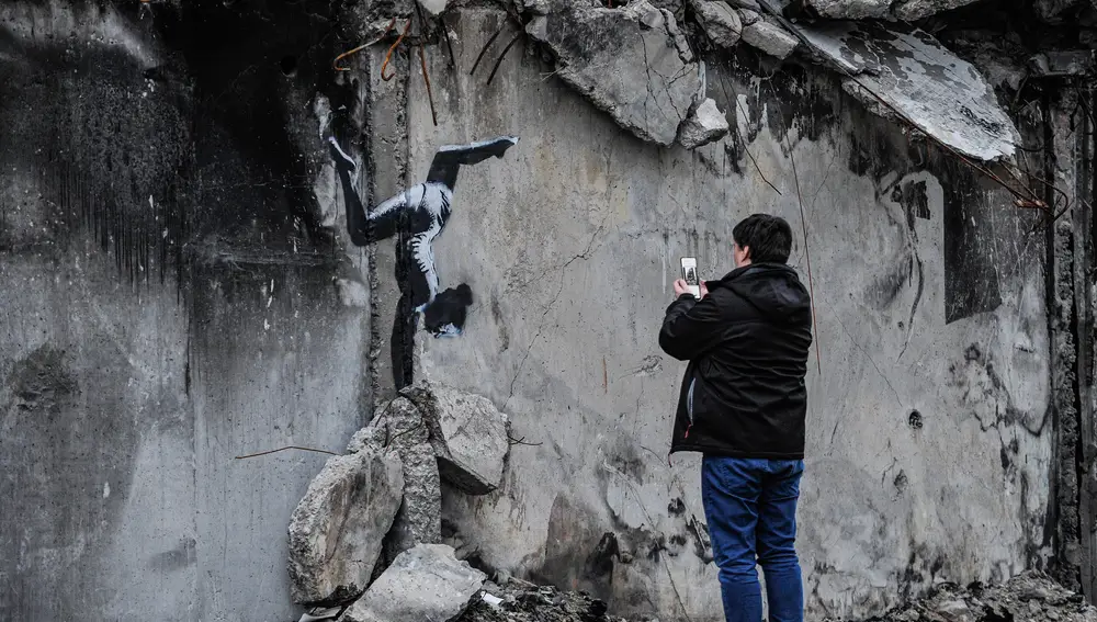 Un hombre toma una foto del grafiti del famoso artista callejero anónimo Banksy