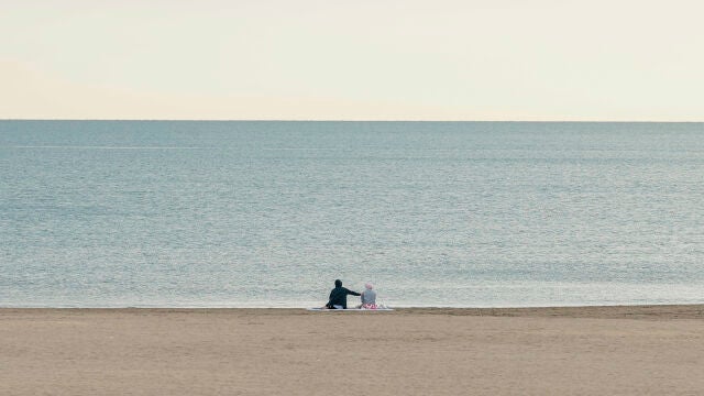 Dos personas disfrutan de la tranquilidad de la playa de la Malvarrosa