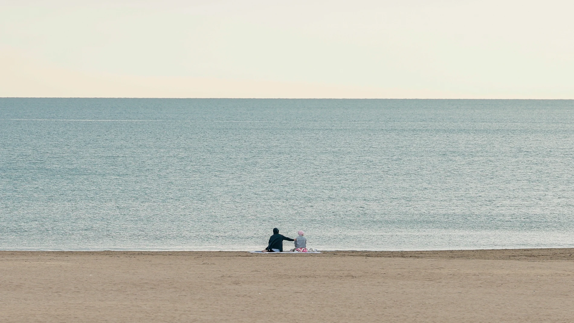 Dos personas disfrutan de la tranquilidad de la playa de la Malvarrosa