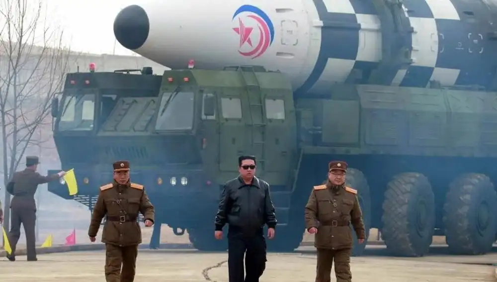 Kim Jong-un escoltado por dos militares delante del poderoso misil que es transportado por un camión