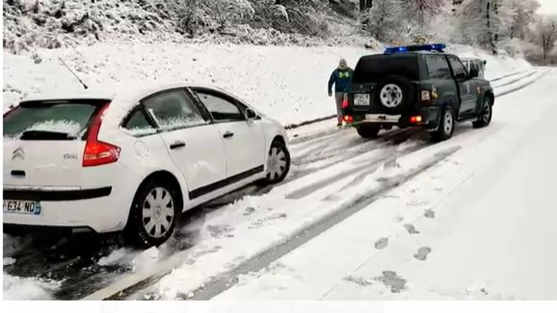 Un vehículo de la Guardia Civil remolca a un coche atrapado en la nieve
