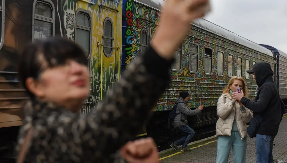 Personas con teléfonos móviles se toman &quot;selfies&quot; cerca de un tren en la estación de tren de Jersón, en el sur de Ucrania
