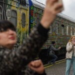 Personas con teléfonos móviles se toman "selfies" cerca de un tren en la estación de tren de Jersón, en el sur de Ucrania