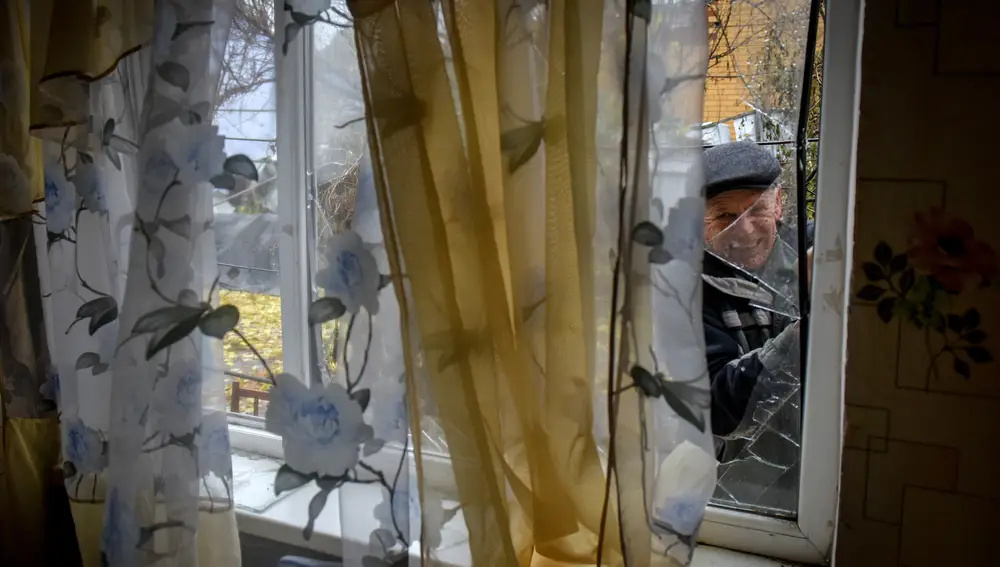 Leonid intenta reparar la ventana de una casa dañada a la que regresó después de la acción de combate en la aldea Posad-Pokrovske