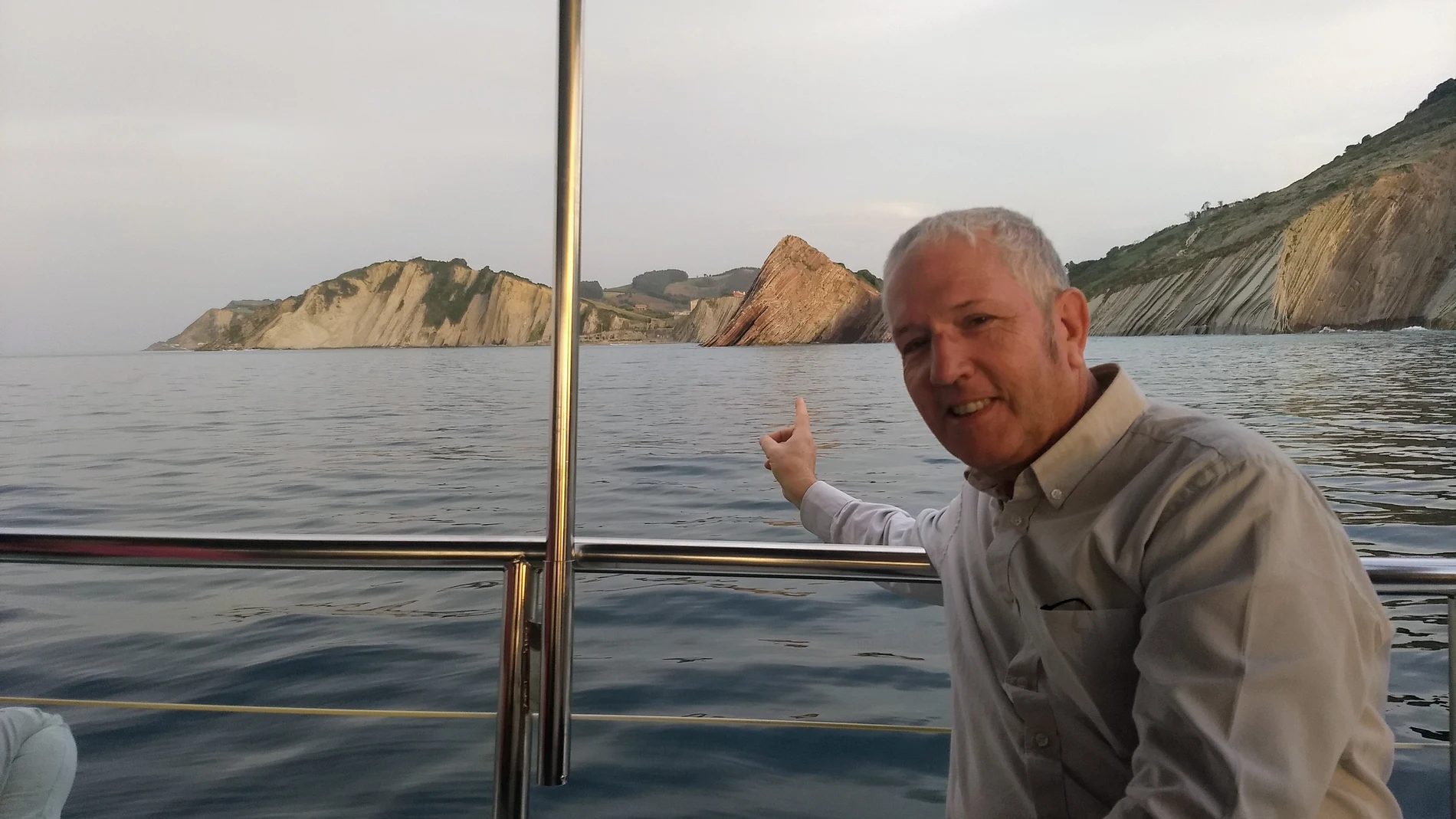 José Luis Gallardo en un barco señalando a un monte que se ve al fondo