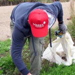 Un voluntario recoge basura en el entorno del río Guadalquivir a su paso por Santiponce