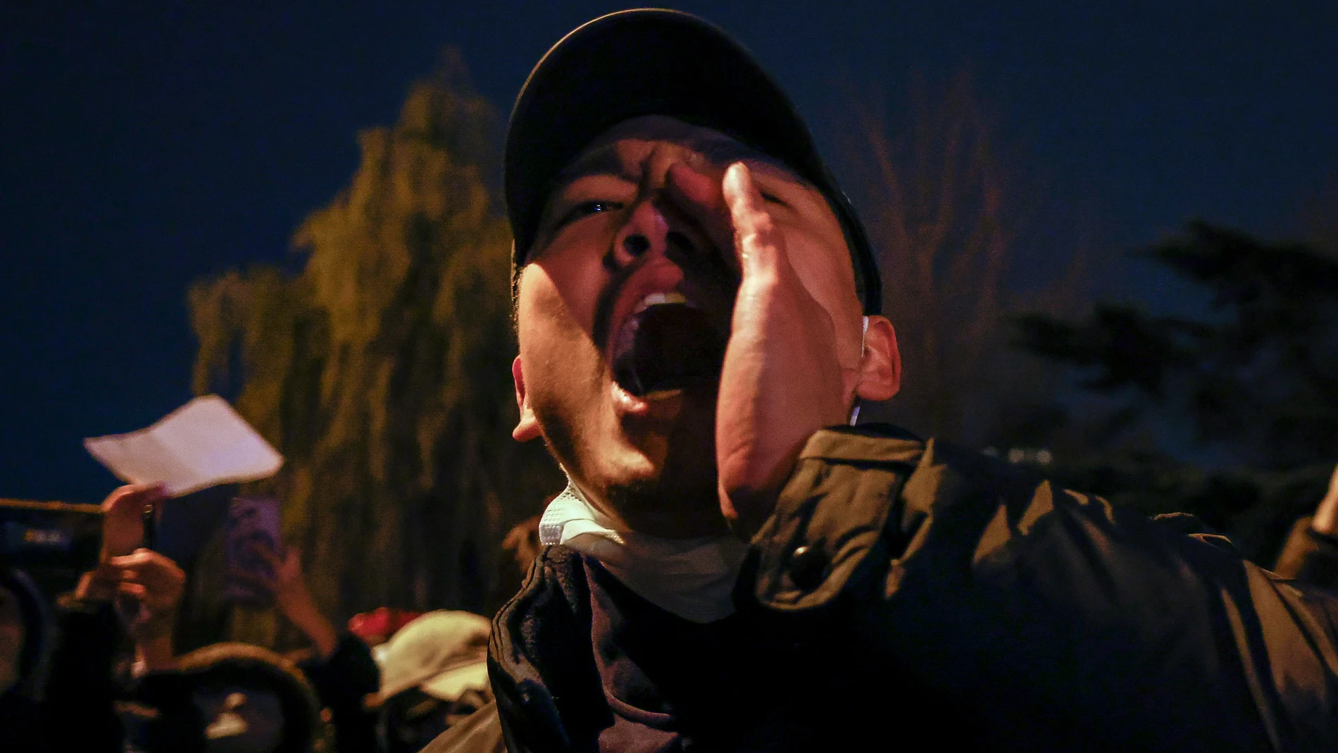Un hombre grita durante una protesta desencadenada por un incendio en Urumqi que mató a 10 personas en Pekín