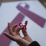 Una mujer sostiene un lazo rojo , símbolo de la lucha contra el virus del sida