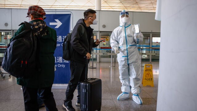 Personal del aeropuerto de Pekín pide a los pasajeros su declaración de salud para poder abandonar la capital china