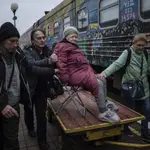 Familiares de Elizaveta, de 94 años, la transportan en un carro de carga al tren de evacuación en Jersón