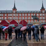 Un grupo de turistas se protegen de la lluvia en la Plaza Mayor de Madrid