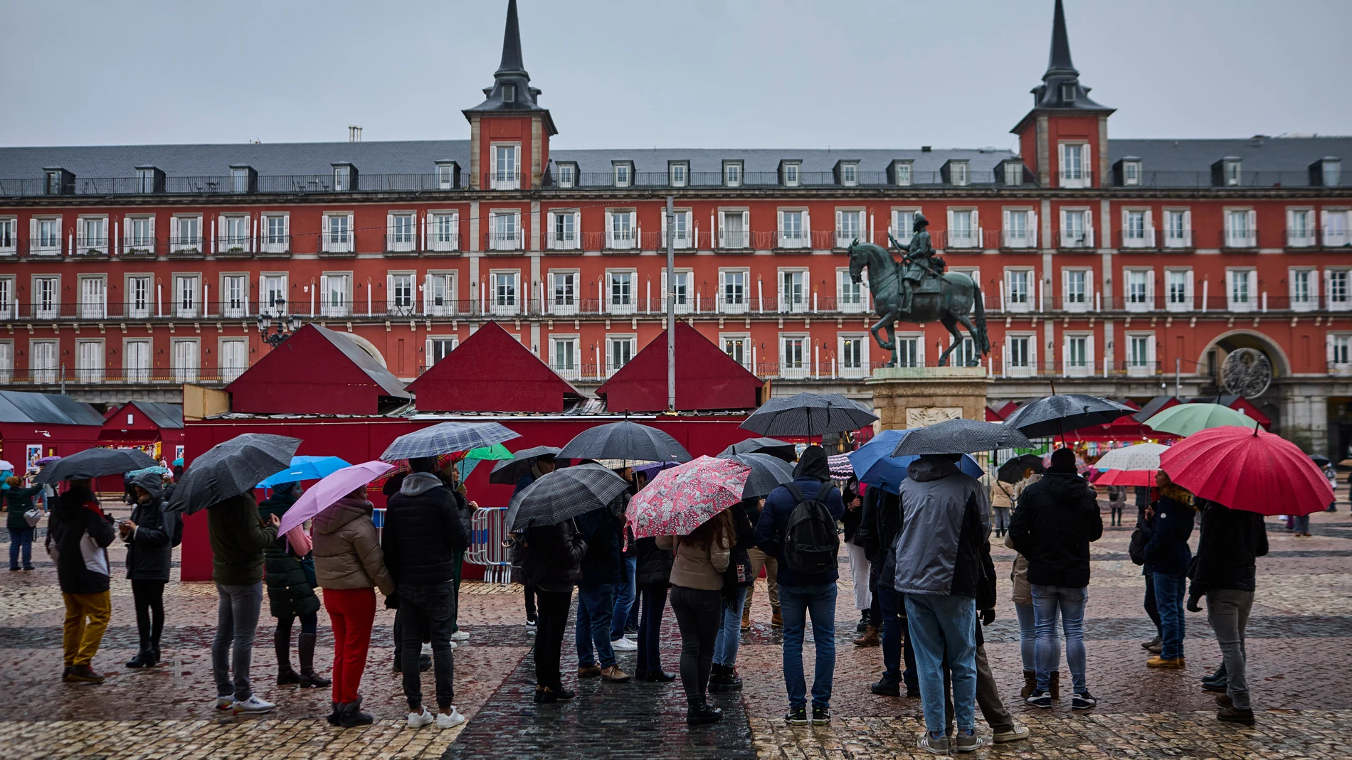 Un grupo de turistas se protegen de la lluvia en la Plaza Mayor de Madrid