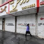 Una mujer iraní pasa junto a tiendas cerradas por la huelga en Teherán