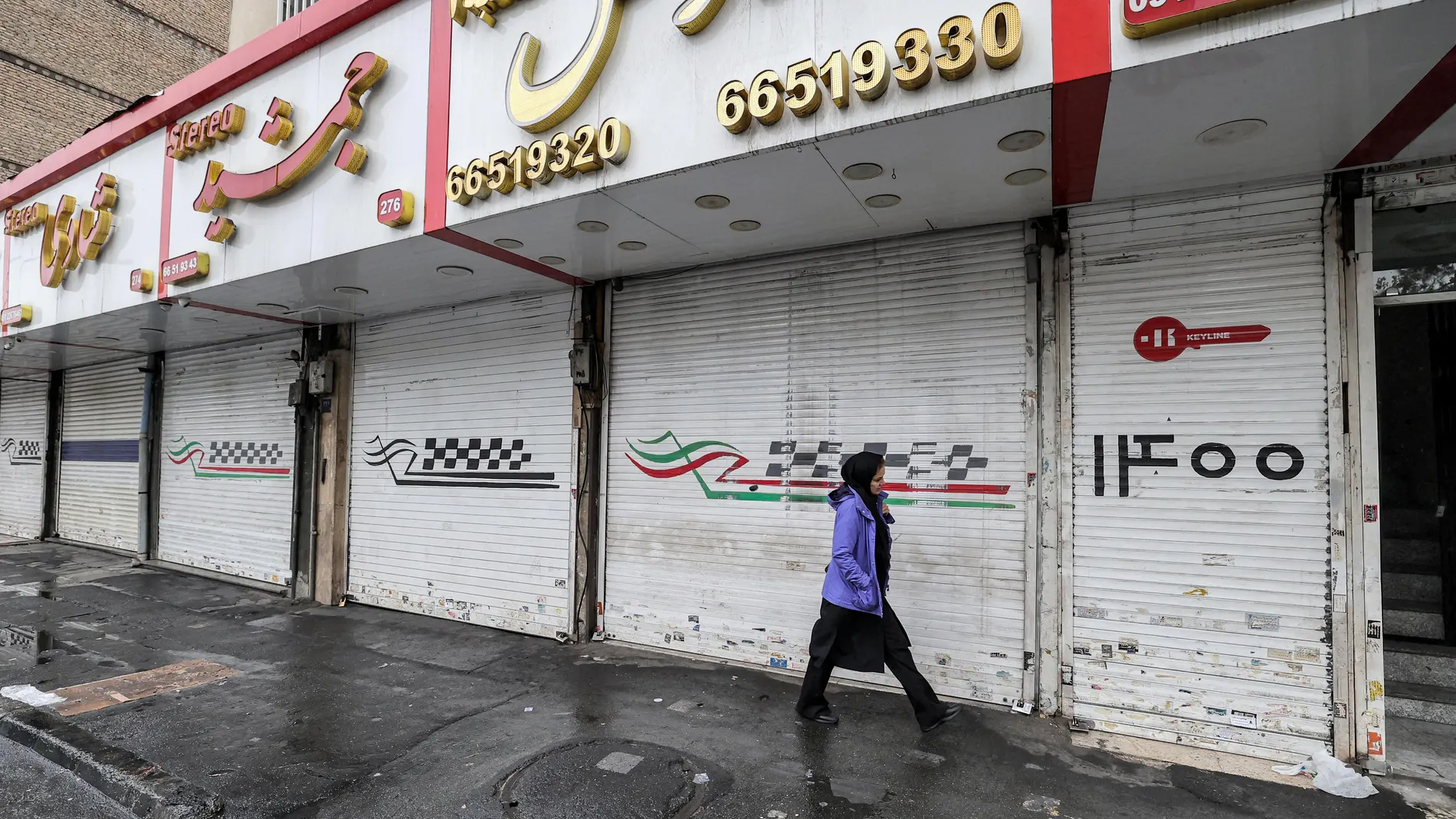 Una mujer iraní pasa junto a tiendas cerradas por la huelga en Teherán