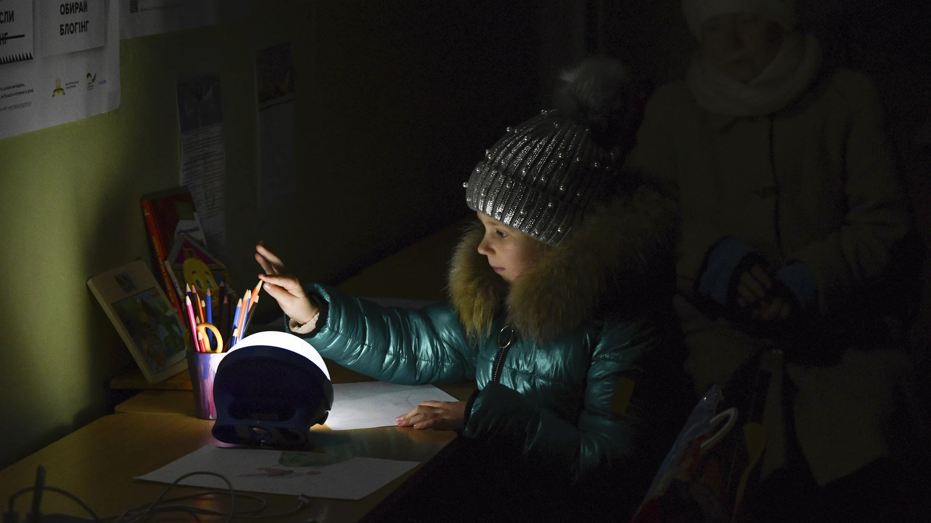 Alexandra, de 11 años, dibuja en un edificio escolar, un "Punto de Invencibilidad", una estación de ayuda construida por el gobierno que permite cargar teléfonos con ayuda de generadores, sirve comida, bebidas y la posibilidad de calentarse, en Kramatorsk, Ucrania