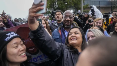 El senador demócrata Raphael Warnock se fotografía junto a una simpatizantes en la jornada electoral