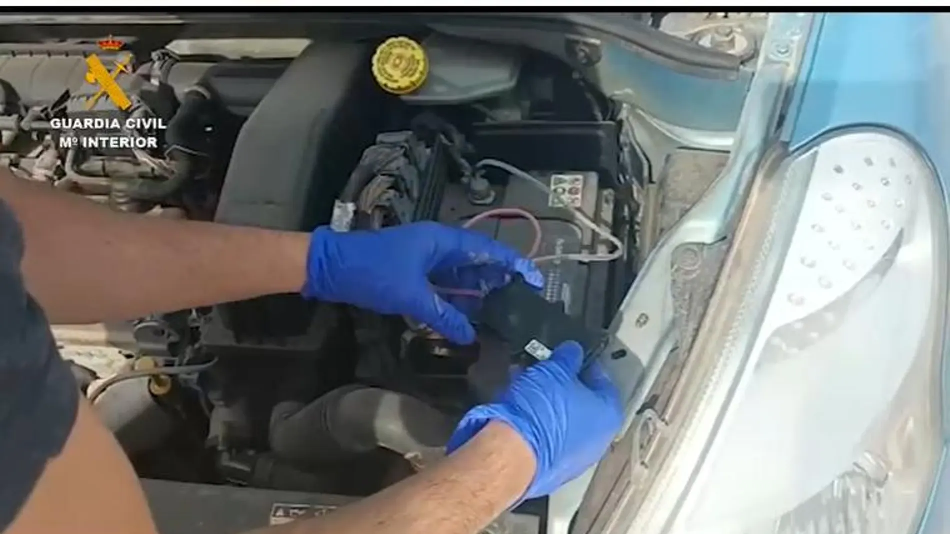 Un agente examina el motor del coche de la mujer para buscar el dispositivo de seguimiento