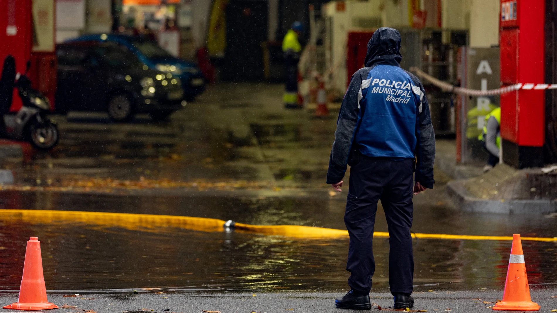 Un agente de Policía en una balsa de agua de una gasolinera, en la Avenida de la Ciudad de Barcelona