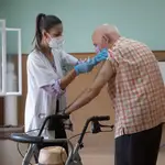 Una enfermera vacuna a un hombre contra la gripe y la covid