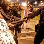 Un policía retiene a una mujer que se manifestaba hoy, en los exteriores de Palacio de Justicia en Lima