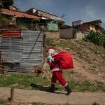 Un hombre vestido de Santa Claus y carga una bolsa de regalos durante la iniciativa "Un Juguete, una buena noticia"