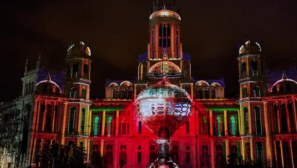 Numerosas personas observan y registran con sus móviles el espectáculo visual realizado mediante videomapping en la fachada del Ayuntamiento de Madrid