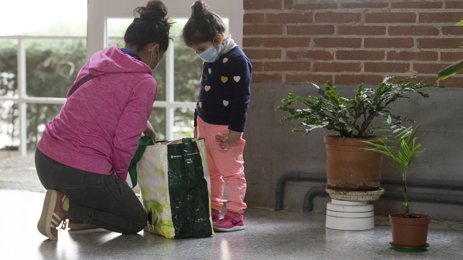 Una madre revisa una cesta de ayuda con alimentos en presencia de su hija