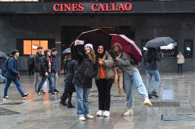 Tres chicas se hacen un 'selfie' bajo sus paraguas en Madrid
