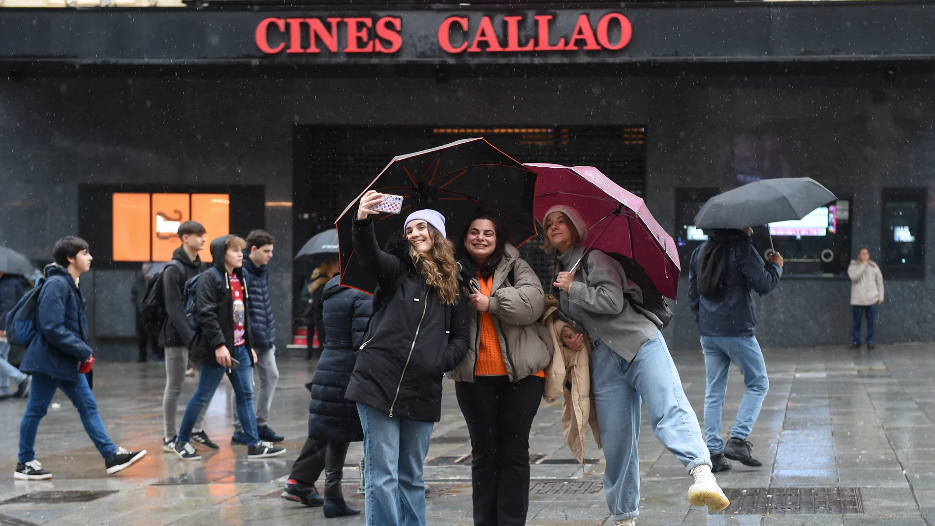Tres chicas se hacen un 'selfie' bajo sus paraguas en Madrid
