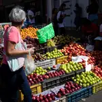 Una mujer mira los precios de las frutas
