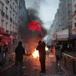 Un miembro de la comunidad kurda ondea las banderas comunistas kurdas junto a una barricada en llamas en la escena del crimen donde tuvo lugar el tiroteo en París