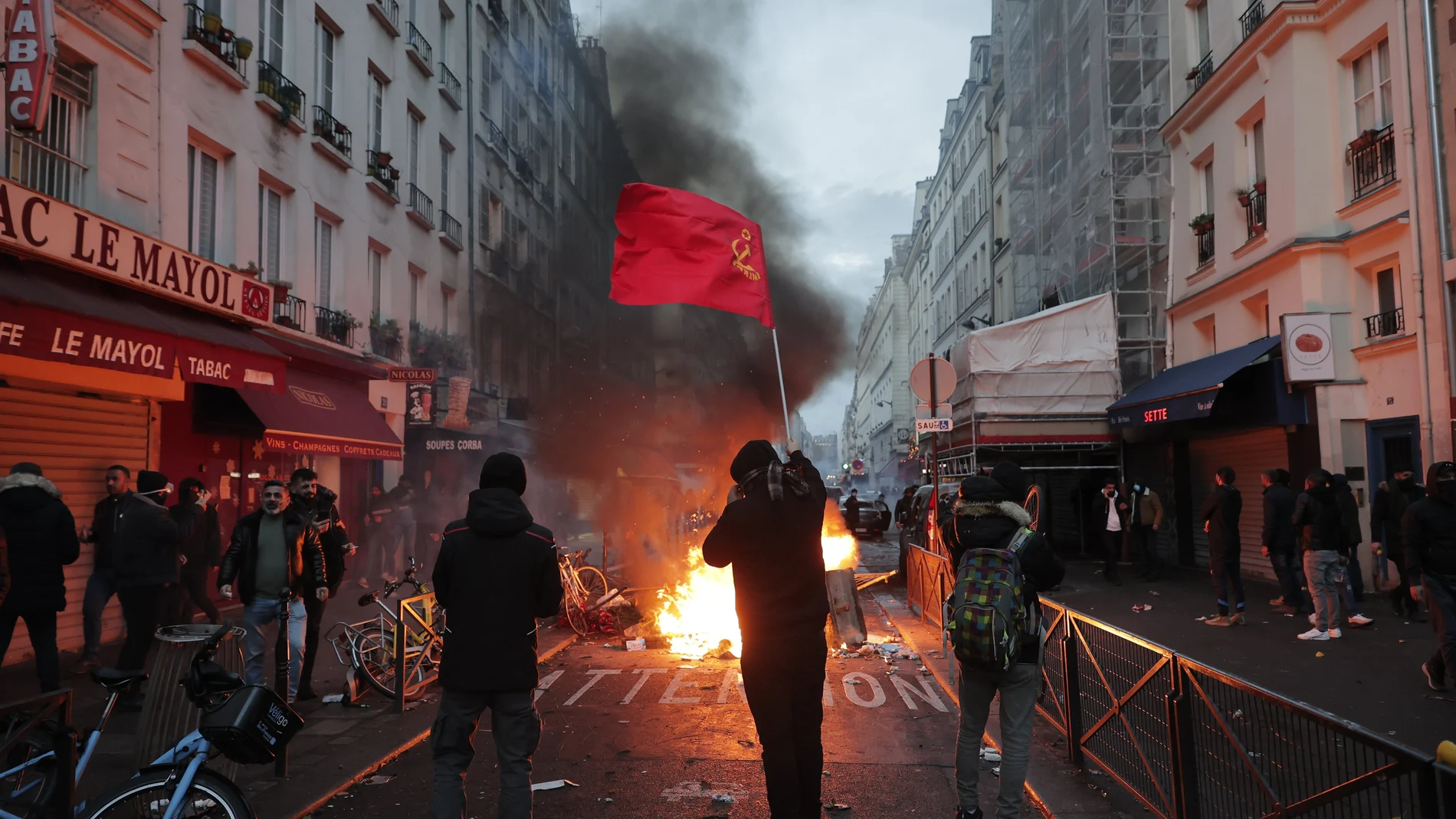 Un miembro de la comunidad kurda ondea las banderas comunistas kurdas junto a una barricada en llamas en la escena del crimen donde tuvo lugar el tiroteo en París