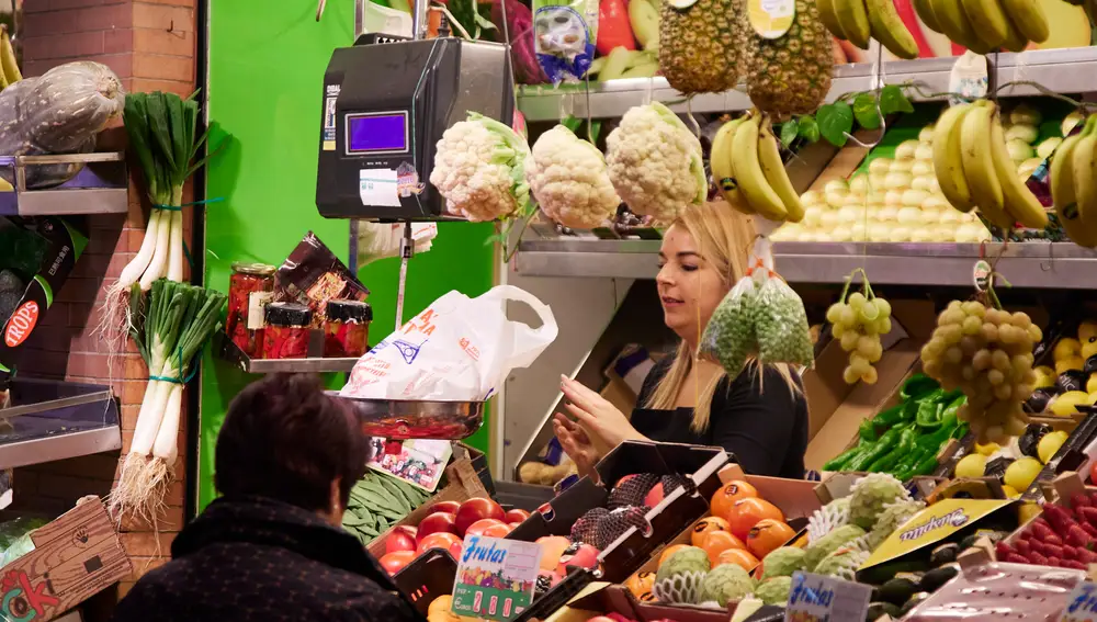 Un dependienta pesa una bolsa con frutas en las compras en los Mercados de Abastos