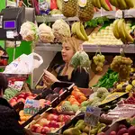 Un dependienta pesa una bolsa con frutas en las compras en los Mercados de Abastos