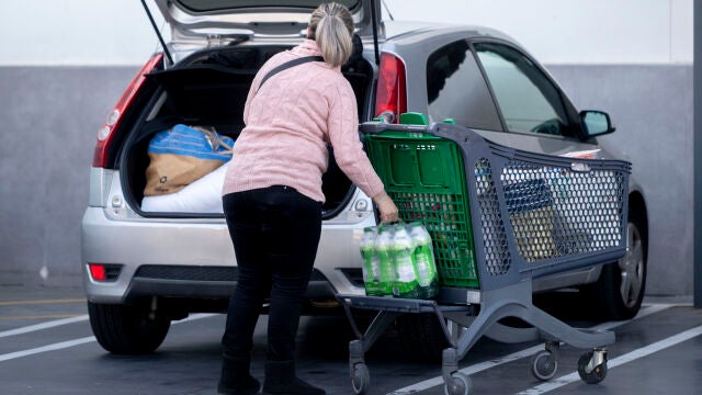 Una mujer mete la compra en el maletero de su vehículo, al salir de un supermercado