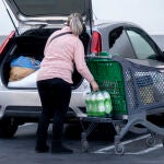 Una mujer mete la compra en el maletero de su vehículo, al salir de un supermercado
