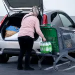 Una mujer mete la compra en el maletero de su vehículo, al salir de un supermercado