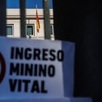 Un cartel en el que se lee: 'Ingreso Mínimo Vital' en las rejas del Ministerio de Inclusión y Seguridad Social
