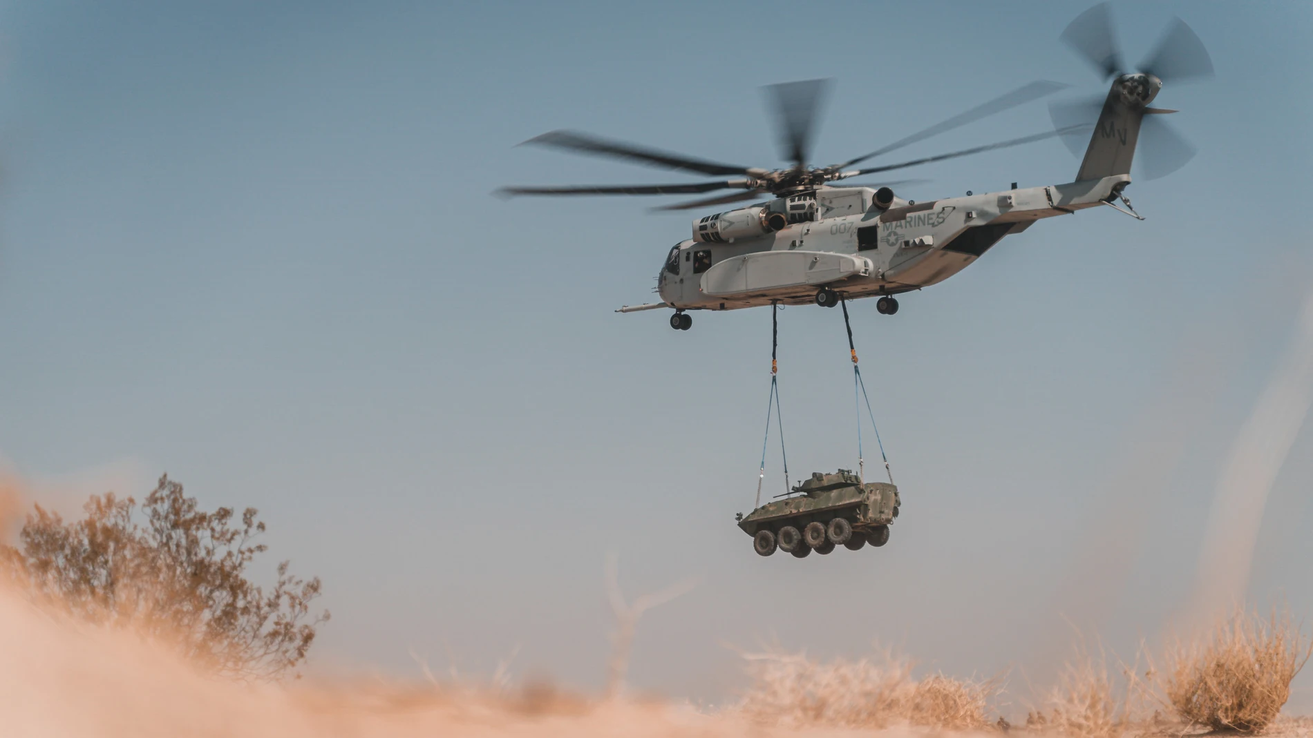 Un Sikorsky CH-53K carga con un vehículo blindado durante las pruebas para su evaluación final