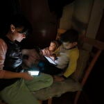 Una madre con sus hijos sentados en el oscuro pasillo de su piso mientras se corta la electricidad durante una alarma antiaérea en Kyiv