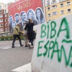 Tres mujeres caminan frente a la lona que han colgado las juventudes del PP en las inmediaciones de la sede del Partido Socialista, a 29 de diciembre de 2022.