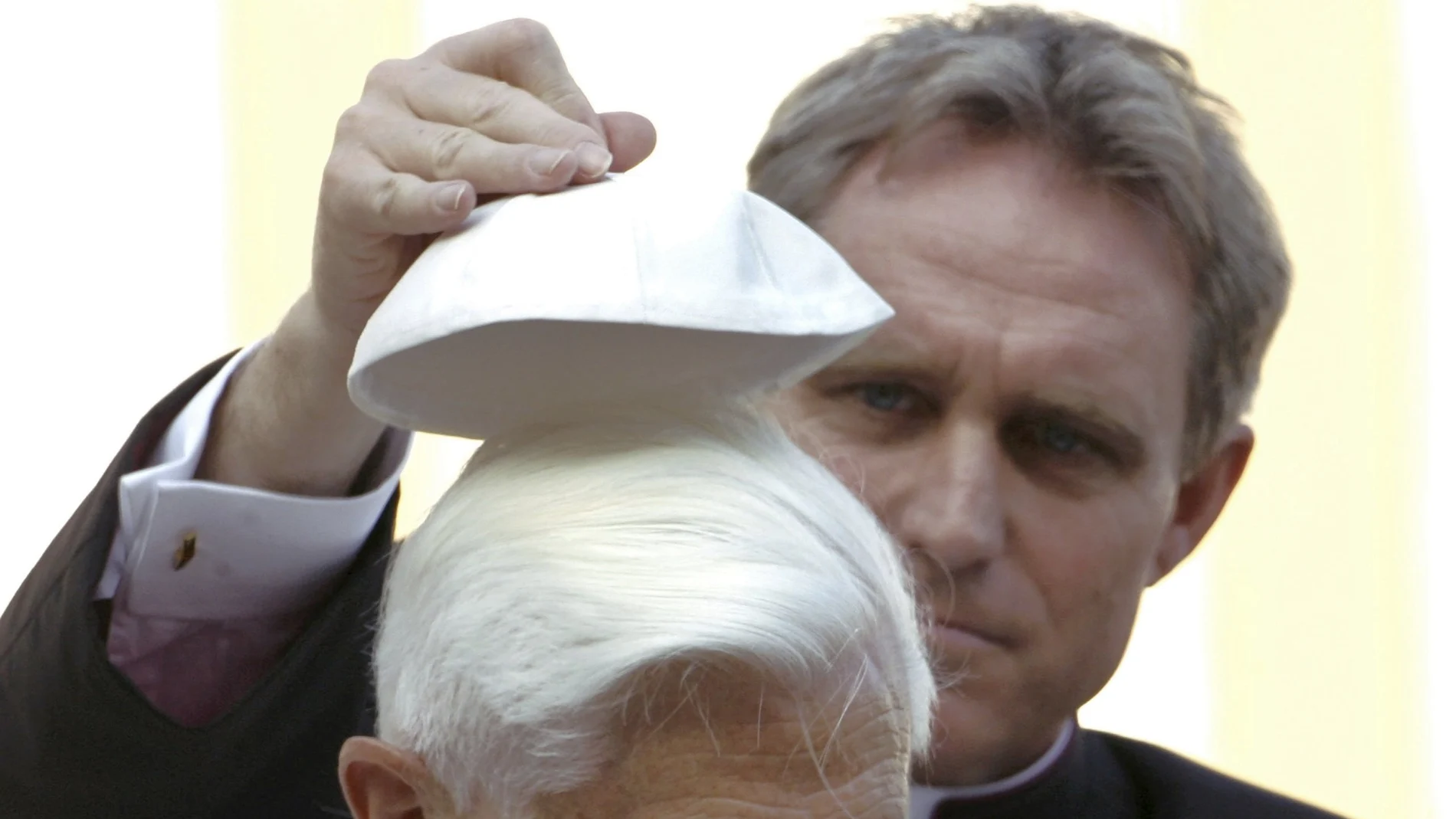 El reverendo Georg Gaenswein, quien fuera secretario de Benedicto XVI, le ayuda a ponerse el solideo en la audiencia general en San Pedro en octubre de 2006