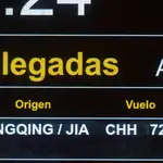 Un vuelo procedente de Chongqing (China) reflejado en el panel de llegadas del aeropuerto Adolfo Suárez Madrid-Barajas