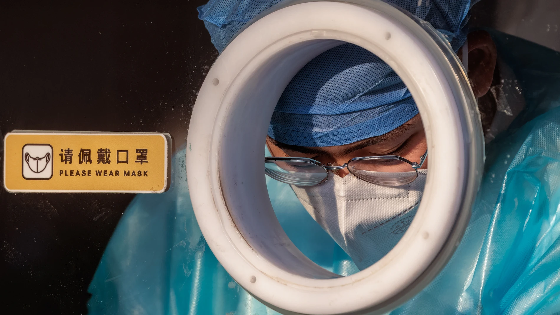 Un sanitario trabaja en una cabina para realizar PCR de coronavirus en Shanghái, China