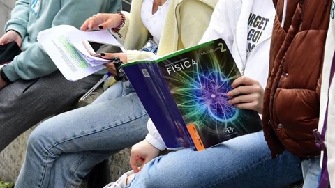 Unos estudiantes consultan sus libros y apuntes antes de un examen