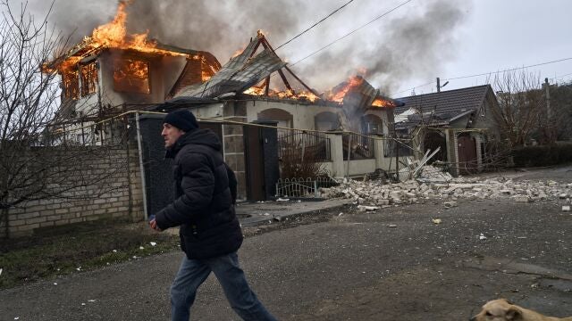 Un residente de Jersón corre junto a una casa en llamas alcanzada por un misil ruso