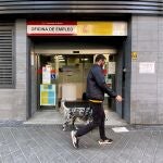 Un hombre pasa con su perro por la oficina de empleo de Acacias, en Madrid