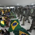 Manifestantes, partidarios del expresidente de Brasil Jair Bolsonaro, se sientan frente a la policía después de dentro del Palacio de Planalto después de irrumpir en él, en Brasilia