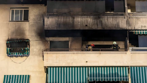 Dos bomberos revisan el estado de la vivienda en el que dos personas han fallecido este lunes en la localidad malagueña de Fuengirola